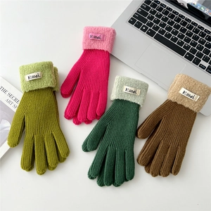 Detail of colorful knitted winter gloves with plush fleece cuffs and woven brand labels