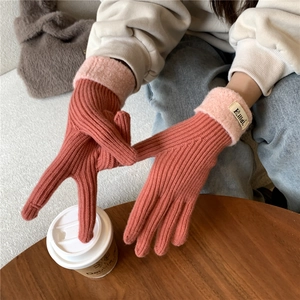 Close-up of coral pink knit gloves with fuzzy light pink cuffs and small fabric label