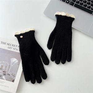 Détail de gants tricotés avec bords en dentelle festonnée blanche et petit bouton doré