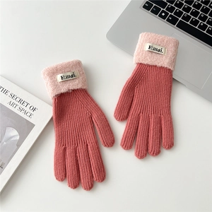 Close-up of pink and red ribbed knit gloves with fuzzy cuffs on a white desk setup