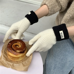 Detail of warm bicolor knit gloves featuring contrast fluffy cuffs and brand logo tag