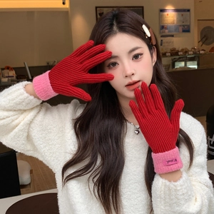 Detail of red and pink knitted gloves with a ribbed texture and brand tag detail