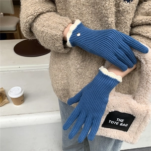 Détails de gants en tricot bleu avec bords volantés blancs et boutons dorés
