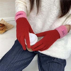 Close-up of red and pink knitted winter gloves with Filldi brand label on cuff