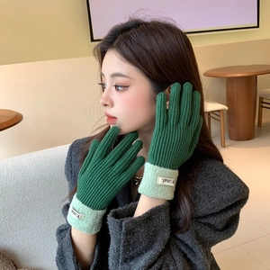 Detail of forest green ribbed knit gloves with soft fleece cuffs and chic brand label