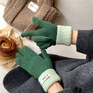 Detail of dark green ribbed knit gloves with fuzzy cuffs and touchscreen fingertips