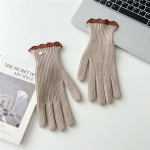 Détail de gants en maille beige avec poignets festonnés marron et bouton doré décoratif