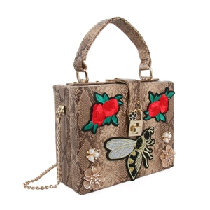 Détail de sac à main motif serpent avec broderie abeille et fleurs perlées latérales