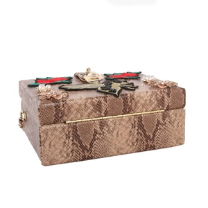 Détail de la broderie d'abeille et des fleurs en cristal sur le sac en cuir serpent