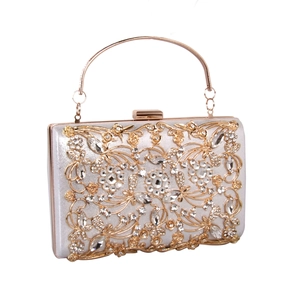 Macro shot of silver satin evening bag with gold floral hollow metal and white rhinestones