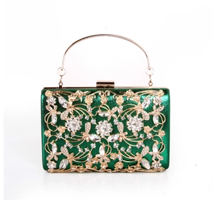 Detailed close-up of green evening clutch with golden floral hollow and rhinestones