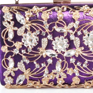 Macro detail of golden hollow floral patterns and rhinestones on a purple evening clutch bag