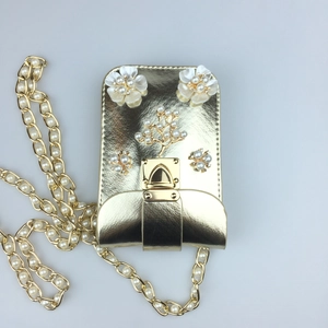 Close-up of golden pearl flower phone bag featuring rhinestone buckle and chain strap