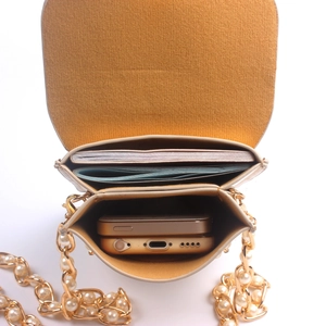 Detail view of the pearl chain phone bag showing yellow suede lining and dual compartments