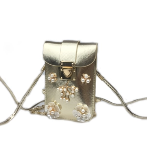 Close-up of gold vertical phone bag with pearl flower applique and metallic snap closure