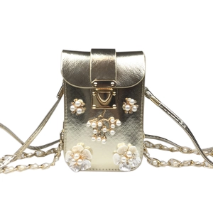 Close-up of champagne gold phone bag with pearl flower decor and metal chain strap
