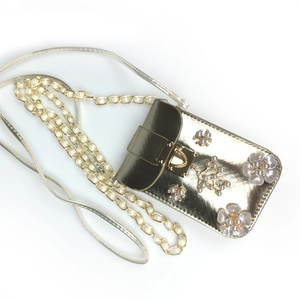 Detail of gold phone bag featuring 3D pearl floral decor and a heart-shaped clasp