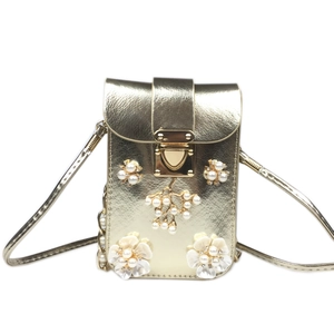 Detail of champagne gold vertical phone bag with 3D white flowers and pearl accents