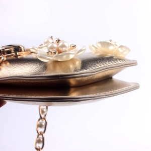 Macro detail of gold evening bag featuring pearl flowers and sparkling rhinestone accents