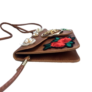 Détail d'une rose brodée et de fleurs de perles sur un sac à bandoulière en cuir marron
