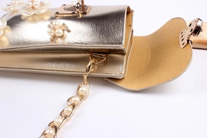 Close-up of gold leather phone bag with floral petals, pearl accents and chain strap