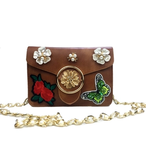 Détail du sac bandoulière marron avec broderie florale et bandoulière en perles