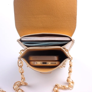 Internal view of beige chain bag with dual compartments, yellow suede lining and pearls