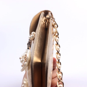Detail view of gold evening clutch featuring pearl flowers and sparkling rhinestones
