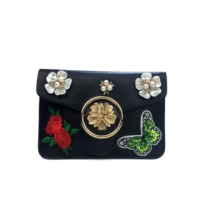 Détail du sac en cuir noir avec fleurs 3D, anneau doré et broderie florale