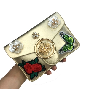 Vue détaillée du cuir doré avec broderie papillon et fleurs de perles sur le sac