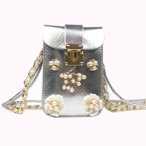 Detailed view of silver crossbody bag with floral pearls and golden chain strap