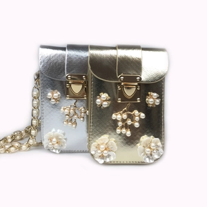 Detail of gold and silver phone bags featuring 3D pearl flowers and heart metal clasps