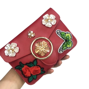 Détail du sac en similicuir rouge avec broderie papillon et fleurs en perles