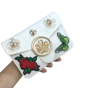 Détail du sac bandoulière blanc avec fleurs de perles et broderie de papillon