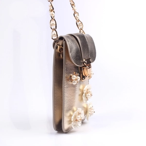 Close-up of champagne gold crossbody bag with 3D floral accents and pearl chain
