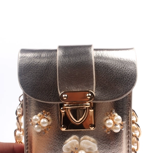 Close-up of champagne gold leather phone bag with pearl and rhinestone flower embellishments