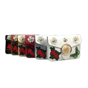 Détails de broderies florales et de paillettes papillon sur de petits sacs bandoulière