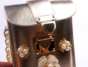 Detail of champagne gold vertical phone bag with pearl flower and rhinestone embellishments