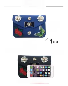 Detail of embroidered butterfly and pearl flower decorations on a crossbody bag