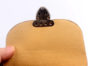 Detailed close-up of brown suede bag texture with golden metallic buckle fastener