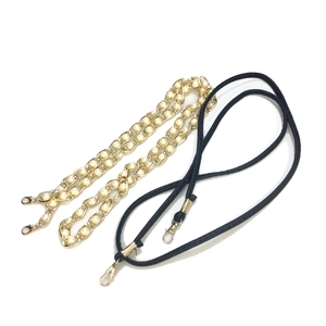 Detail of elegant gold metal chain with white pearls and black cord with lobster clasps