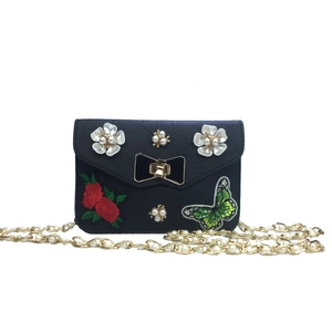 Detail of black crossbody bag featuring butterfly embroidery, pearls, and floral accents