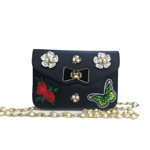 Detail of black crossbody bag with rose embroidery and pearl flower decorations