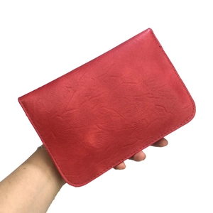 Detail of red pebbled leather rectangular clutch bag with meticulous hand stitching