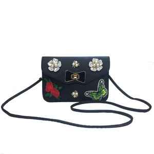 Close-up of butterfly embroidery and pearl flowers on the black leather crossbody bag