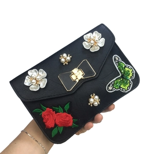 Detail of embroidered butterfly and floral pearls on black crossbody bag