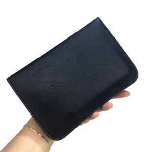 Close-up of black litchi grain leather clutch bag featuring fine stitching and handheld view