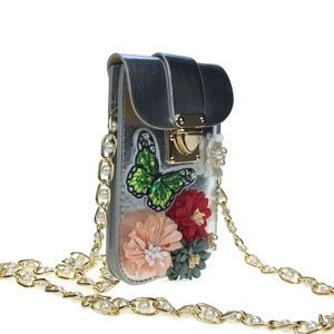 Close-up of silver mini bag with 3D floral appliqués and pearl chain strap detail