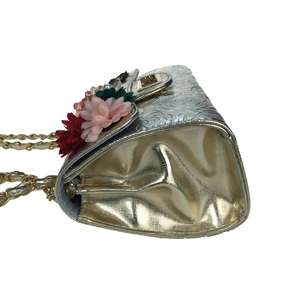 Detail view of gold evening bag with rose embossing, 3D floral accents, and pearls