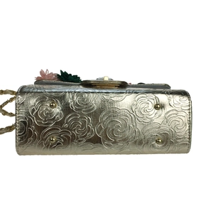 Detail view of gold evening bag with 3D satin flowers and protective metal feet